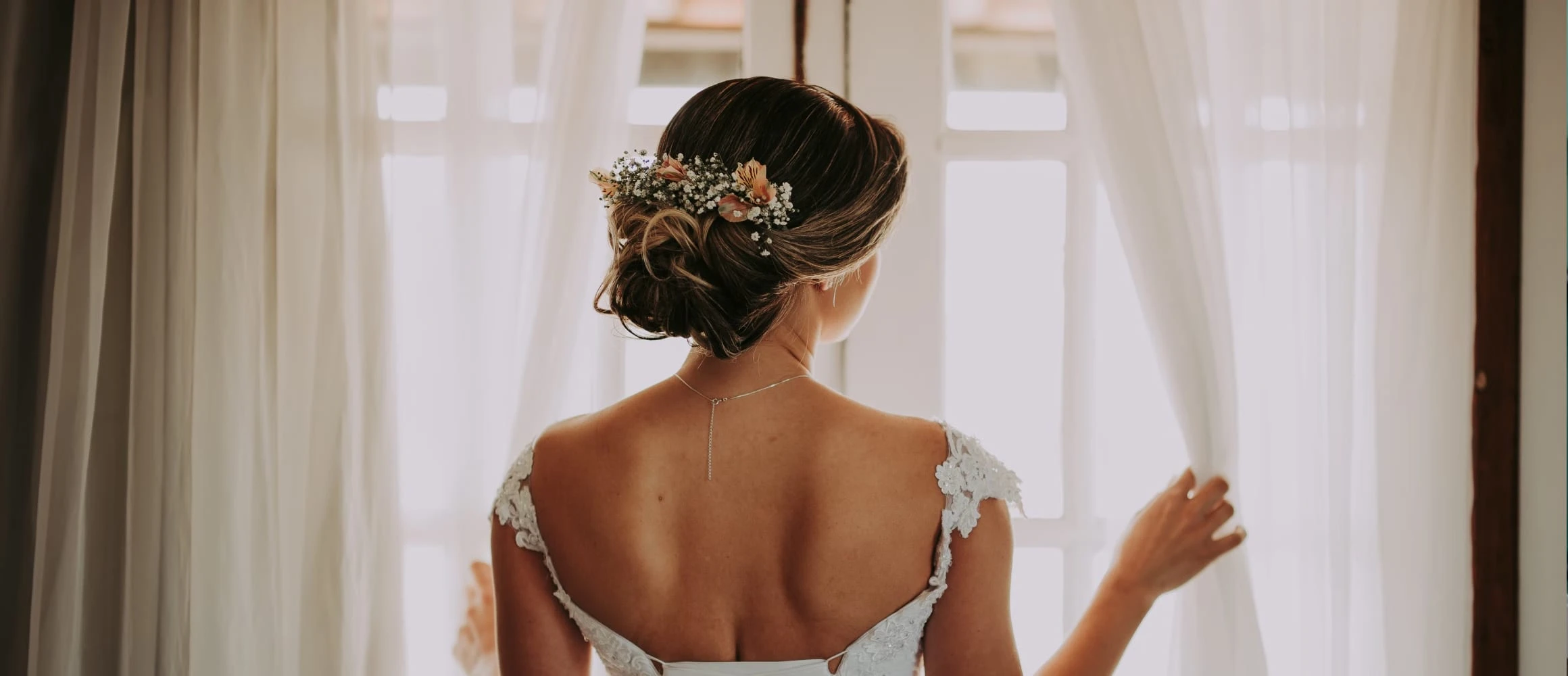 A bride looking looking out through curtains