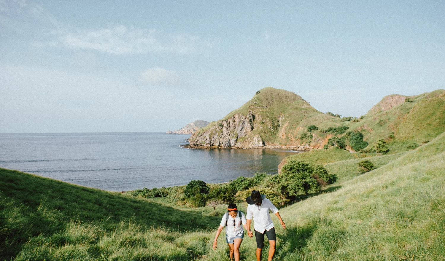 A couple walking up a grassy hill