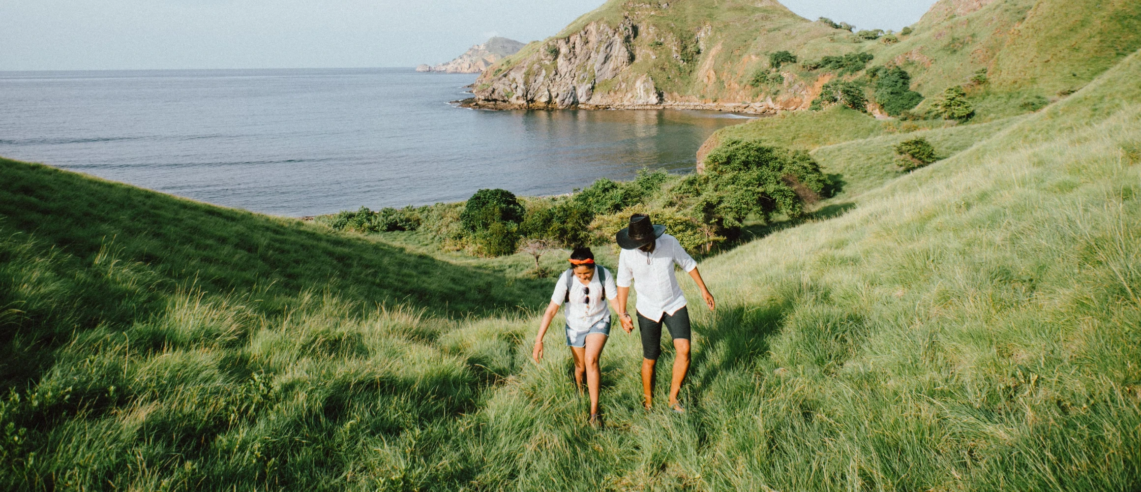 A couple walking up a grassy hill