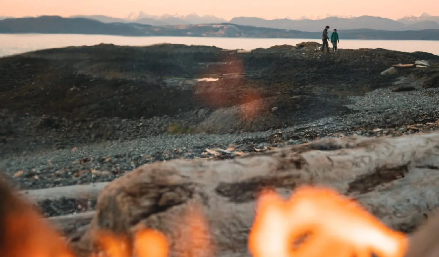 Couple walking on a beach near a bonfire