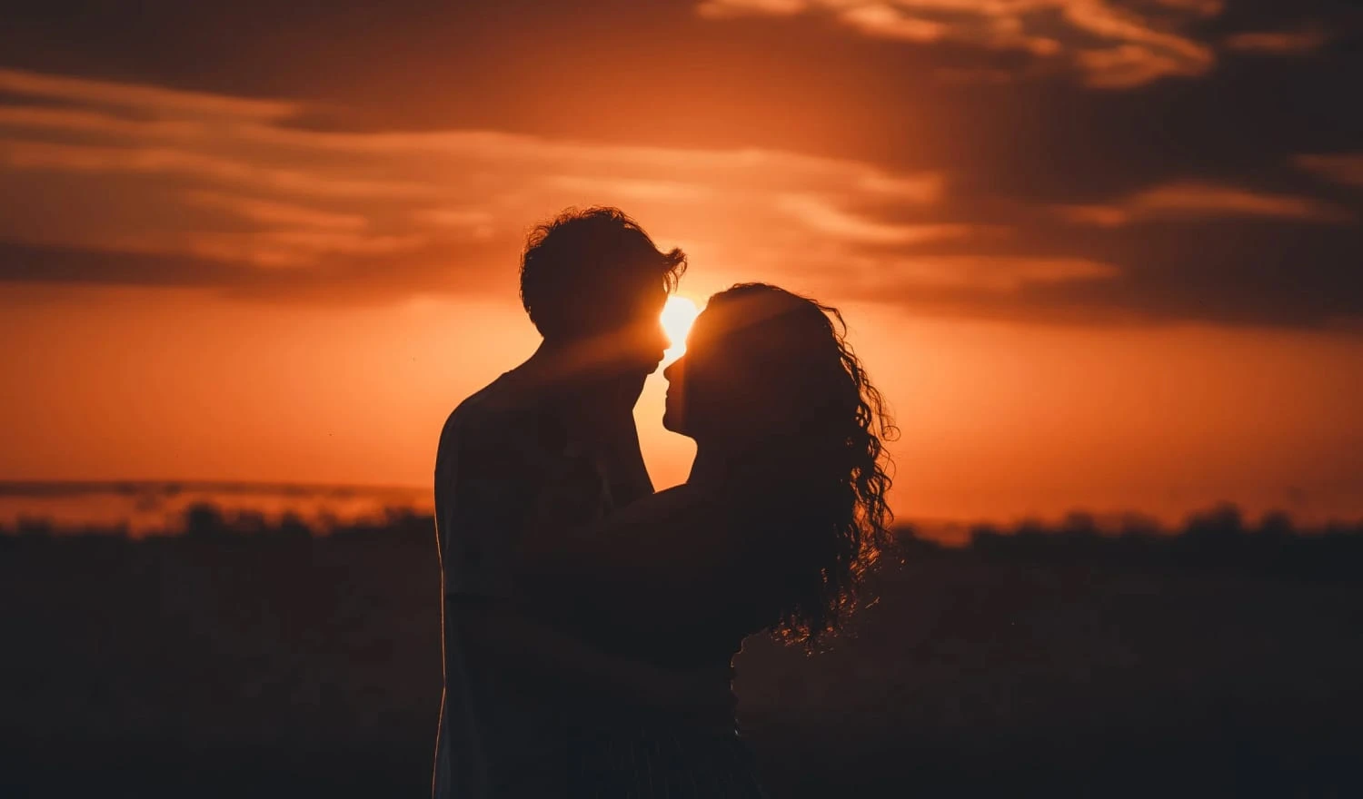 Two people kissing at sunset