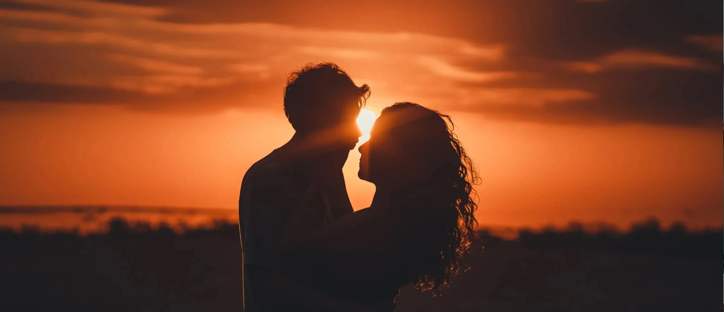 Two people kissing at sunset