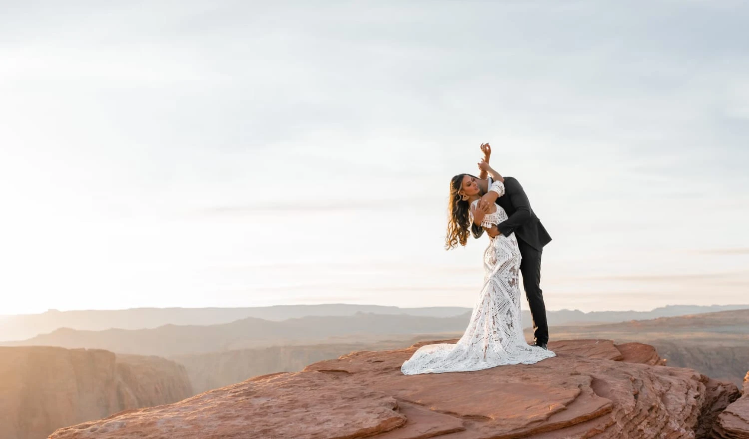 A newly married couple standing on a rock