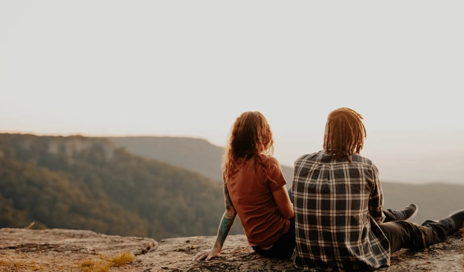 Couple sitting on a rock staring at mountains