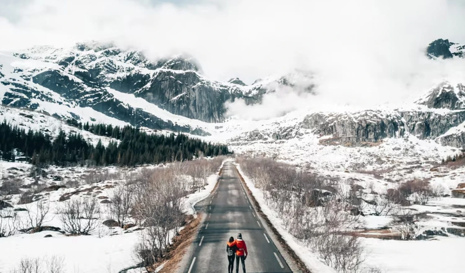 Two people standing on a snow filled road