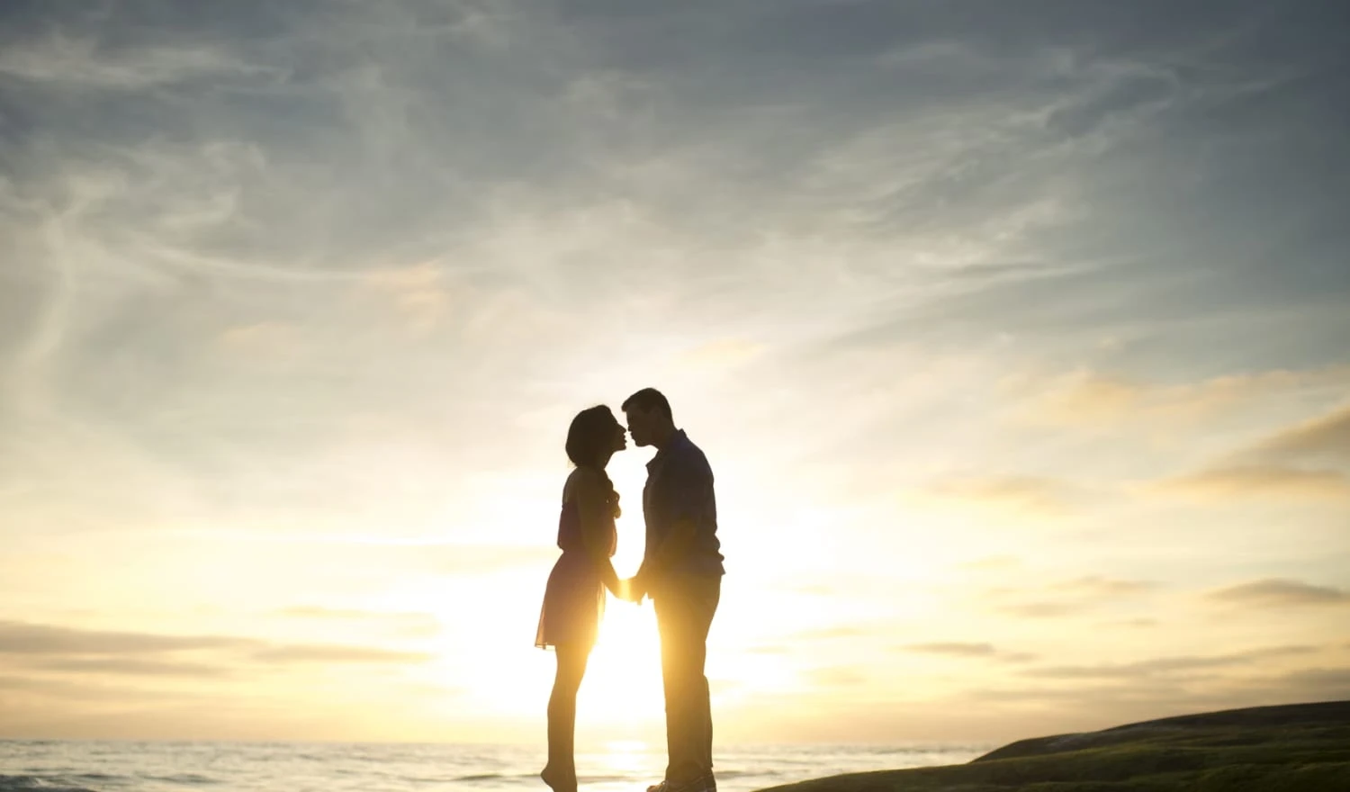 Two people kissing as the sun goes down