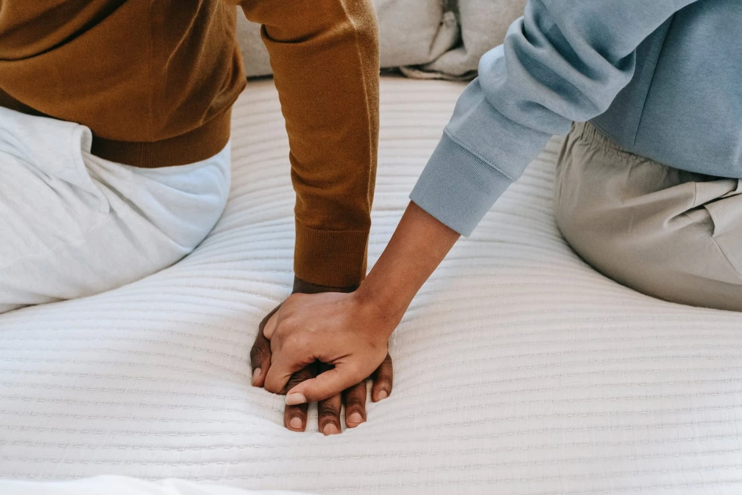 A couple holding hands on a bed