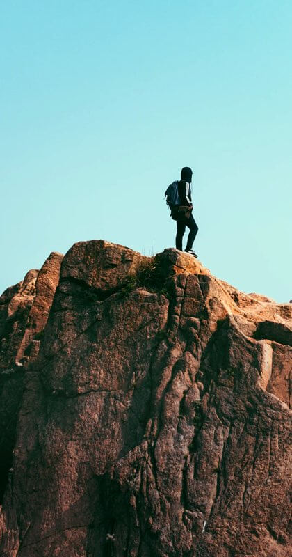 A solo hiker high up on a mountain surronded by blue sky