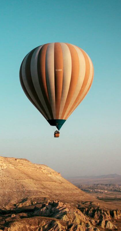 A hot air balloon soaring over smokey mountains