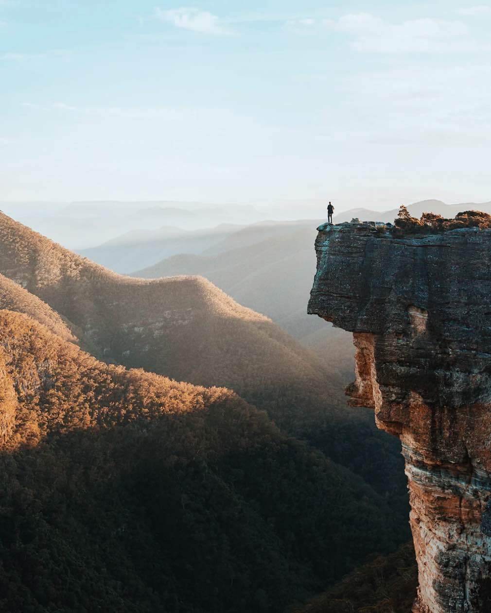 A silhouette perched on a cliff overlooking the hinterland