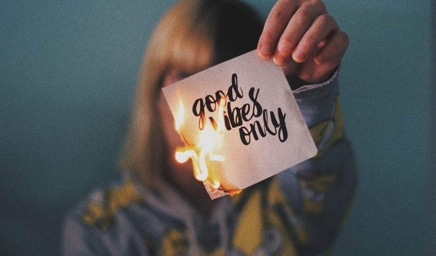 A woman holding a card saying 'Good vibes only'