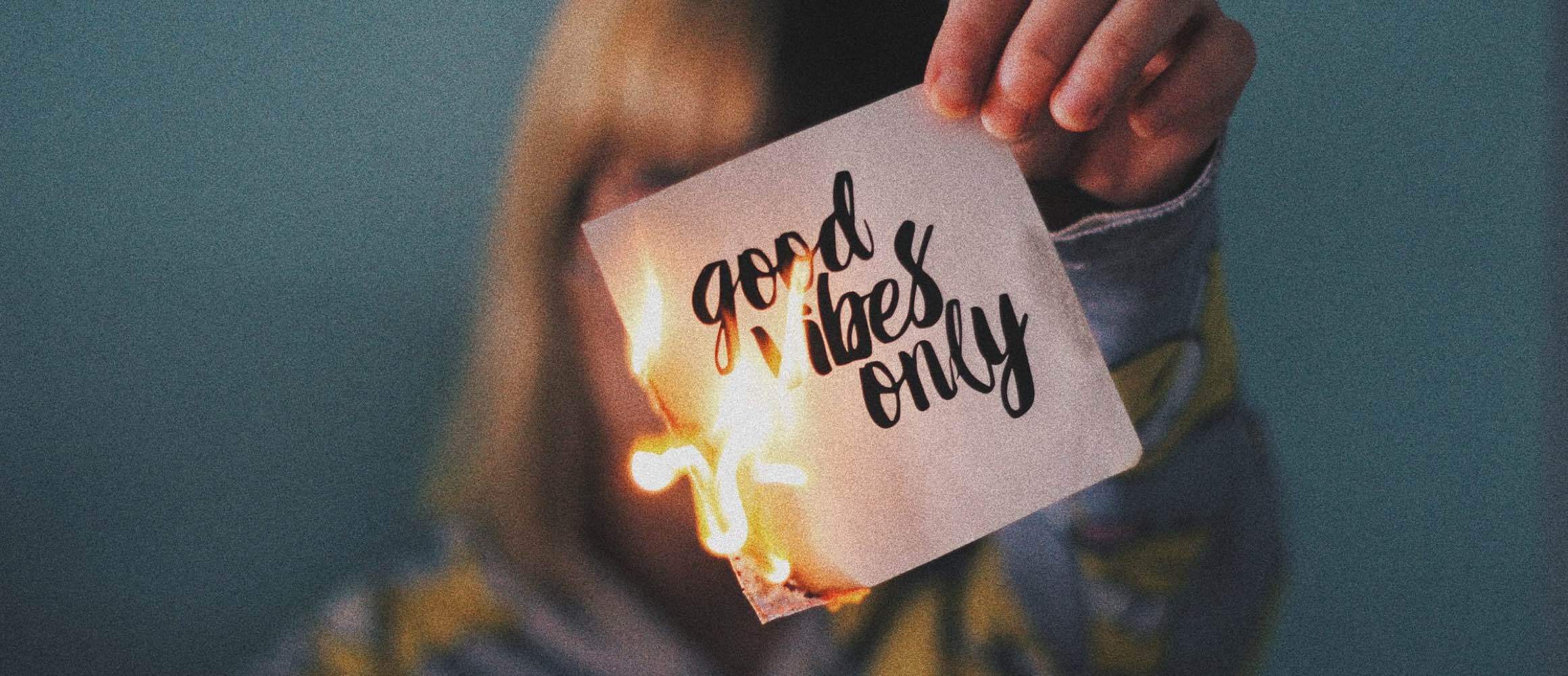 A woman holding a card saying 'Good vibes only'