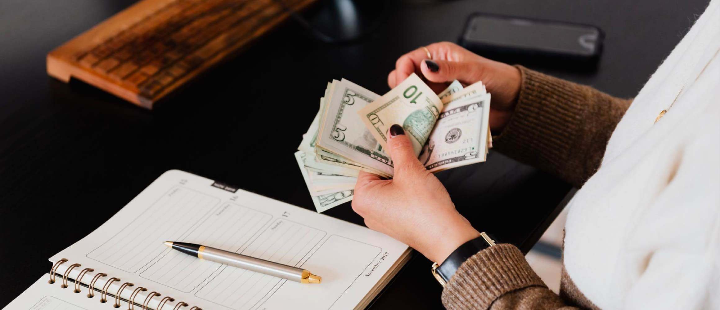 A woman flipping throguh cash and writing in a book