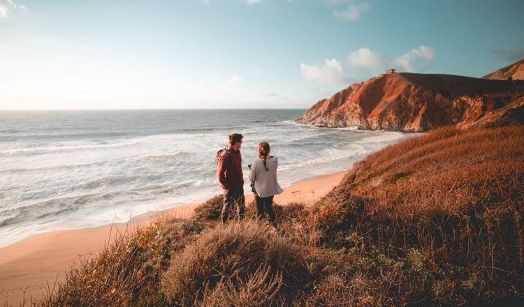 A couple overlooking a beach at sunset