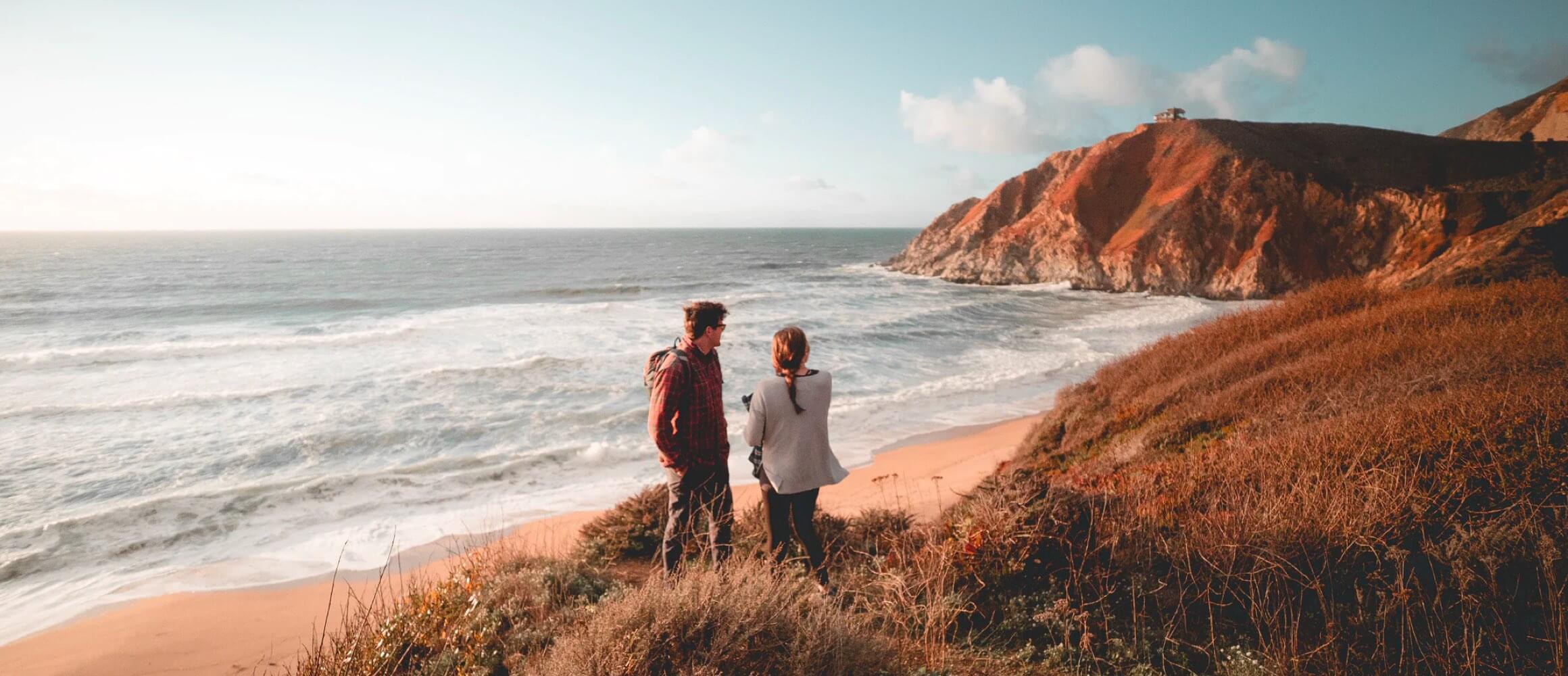 A couple overlooking a beach at sunset