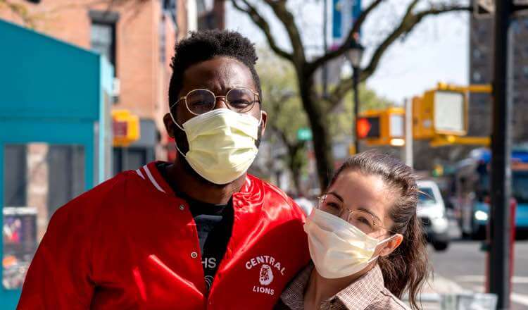 Masked wearing couple posing in a busy street