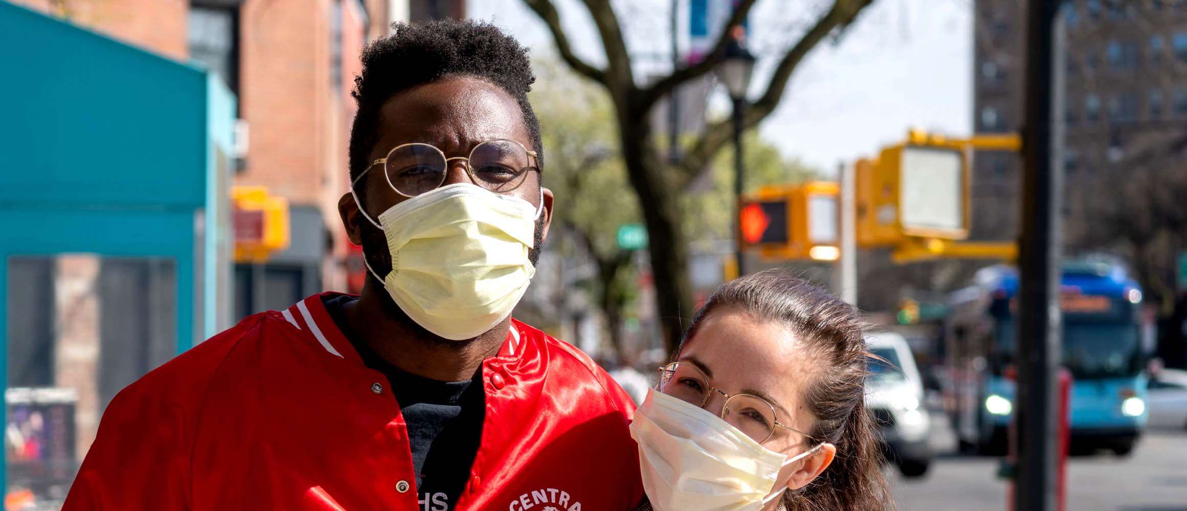 Masked wearing couple posing in a busy street