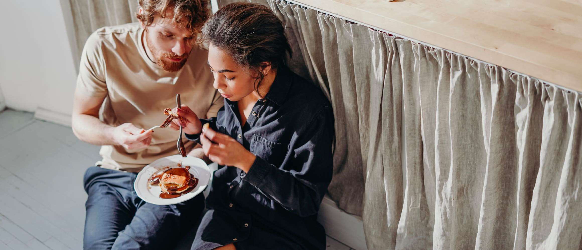 A couple eating pancakes in their kitchen