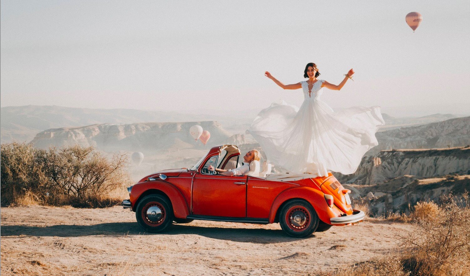 A couple celebrating from a vintager car