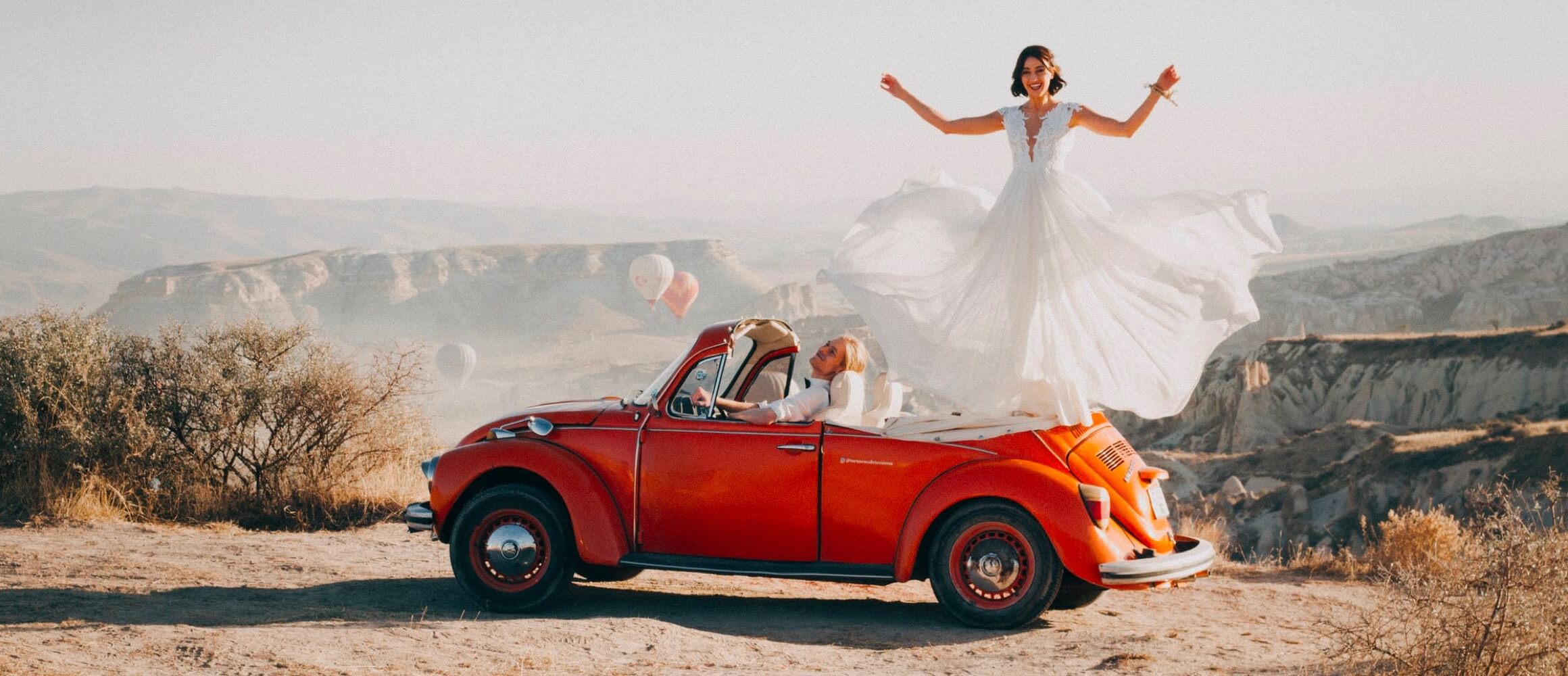 A couple celebrating from a vintager car