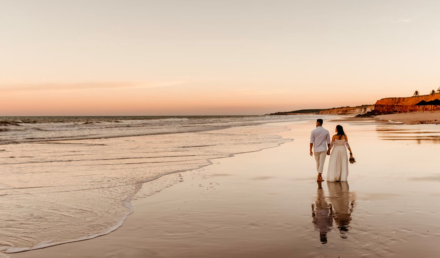 A couple walking down the beach holding hands