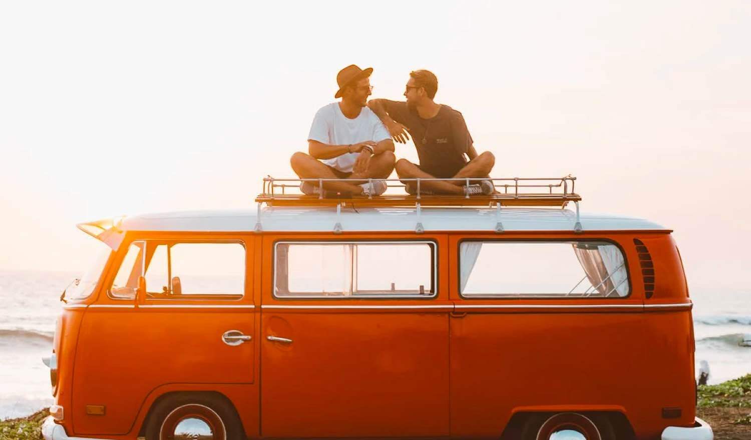 Couple who are on holiday sitting on their van roof