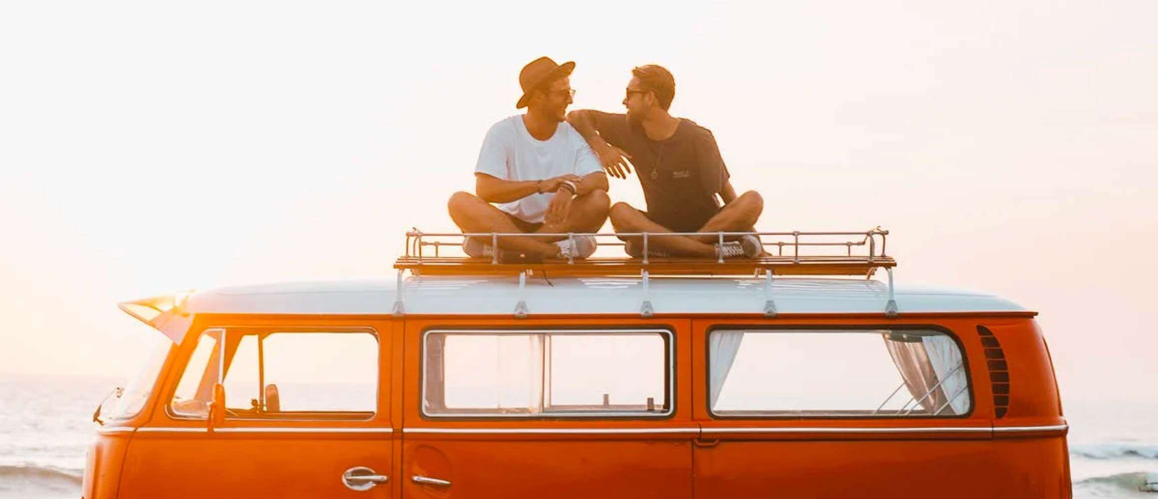 Couple who are on holiday sitting on their van roof