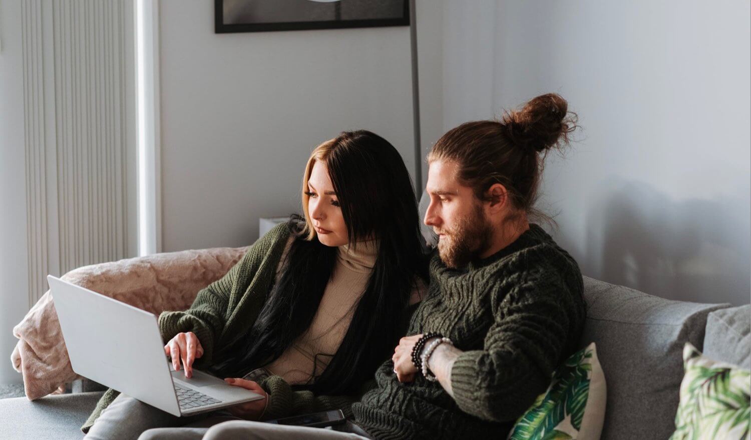 Two people looking at a device on the couch