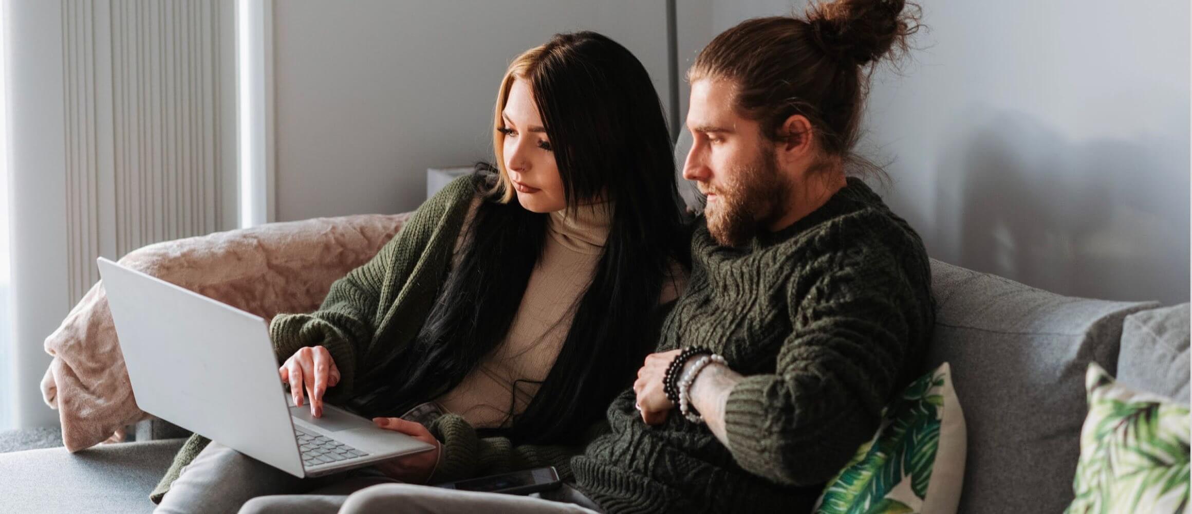 Two people looking at a device on the couch