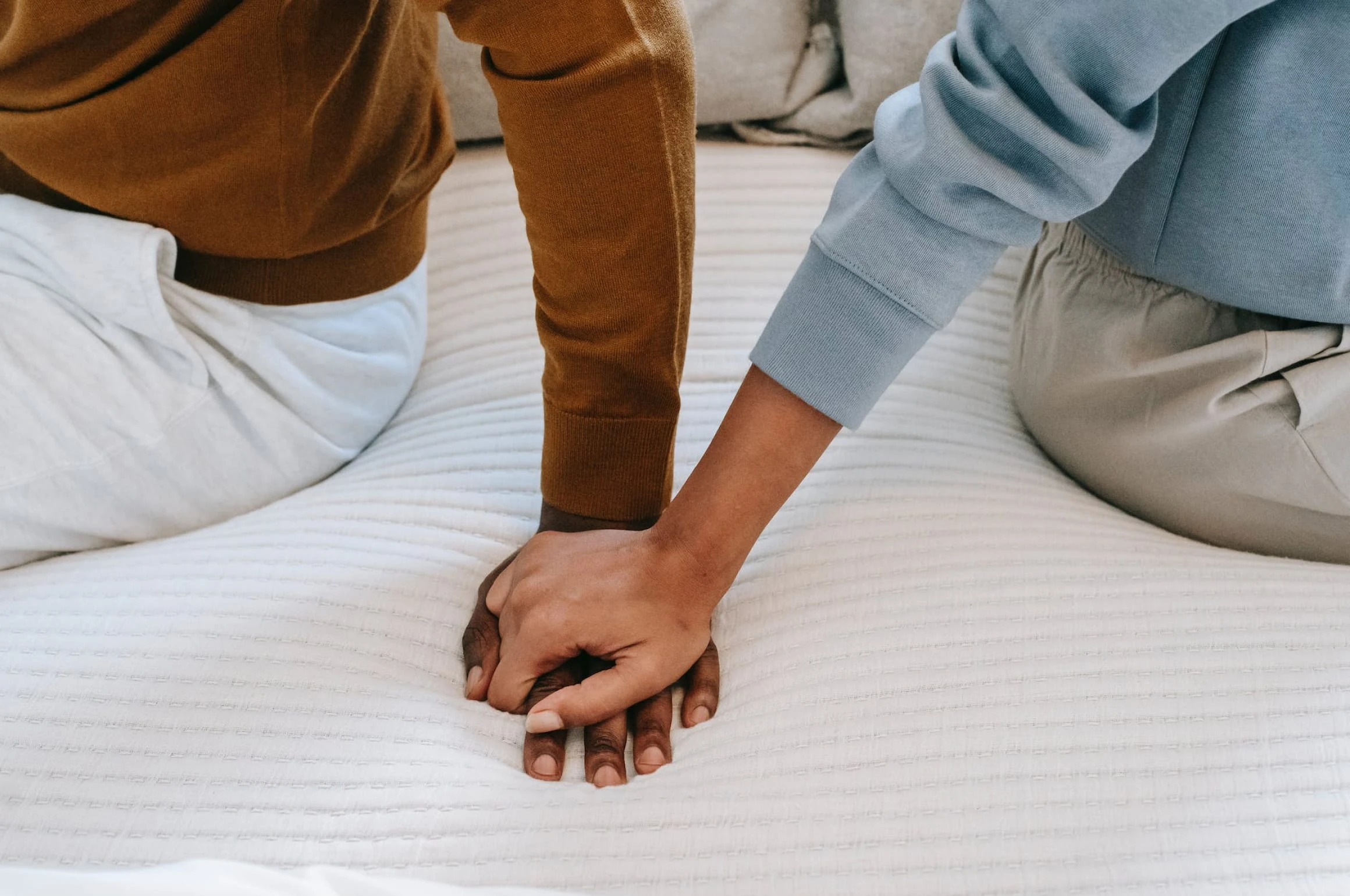 A couple holding hands on a bed