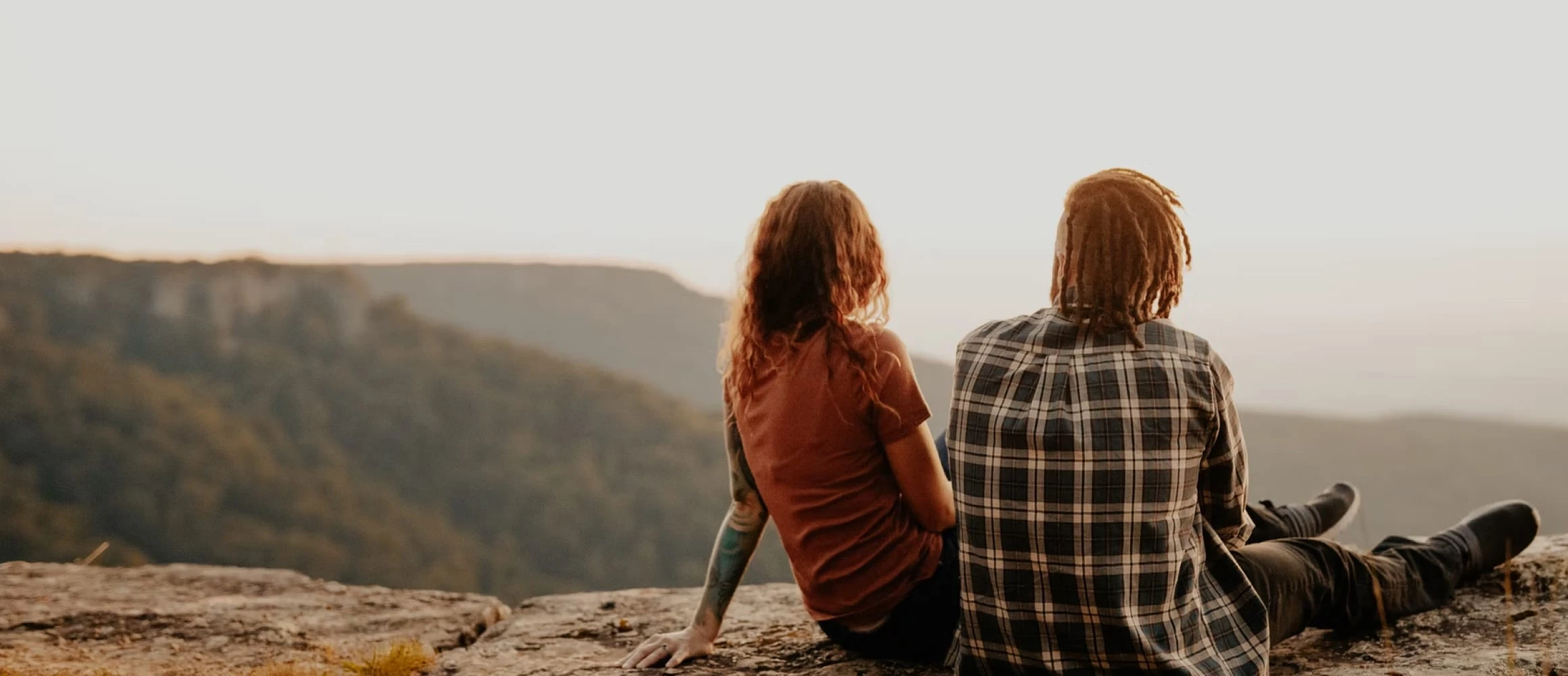 Couple sitting on a rock staring at mountains