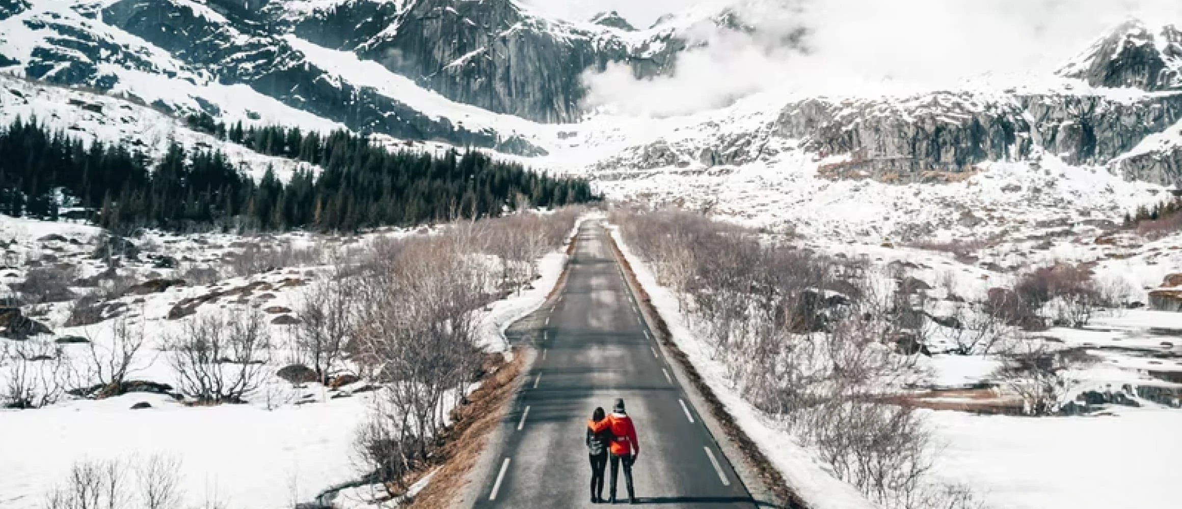 Two people standing on a snow filled road