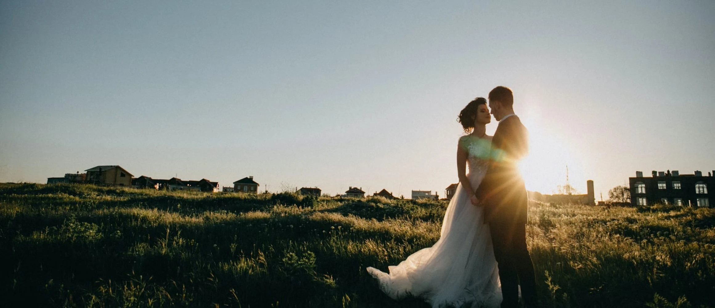 Newlyweds standing on a grassy hill