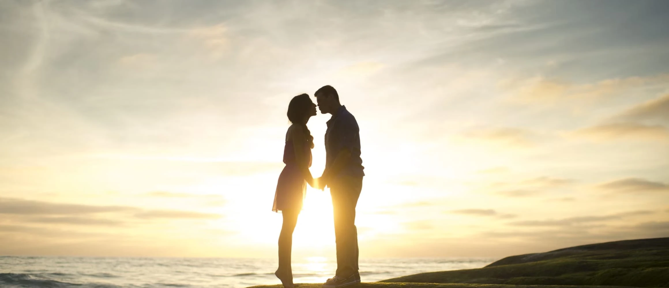 Two people kissing as the sun goes down